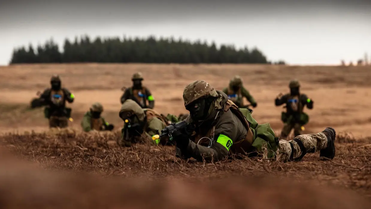 Militairen liggend in het veld, ze richten hun wapens.