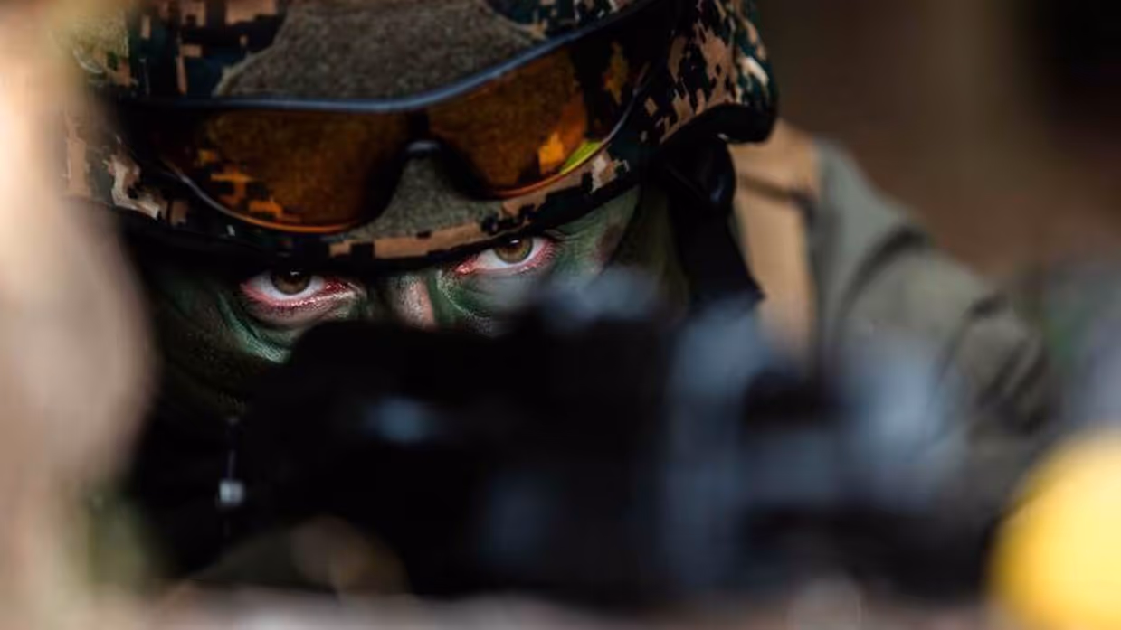 Militair met helm en gecamoufleerd gezicht. Alleen de ogen zijn zichtbaar.