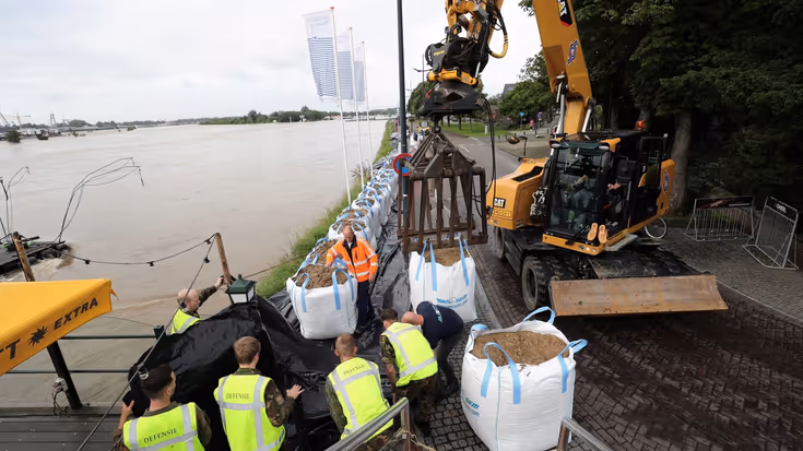Militairen helpen bij het plaatsen van zandzakken.