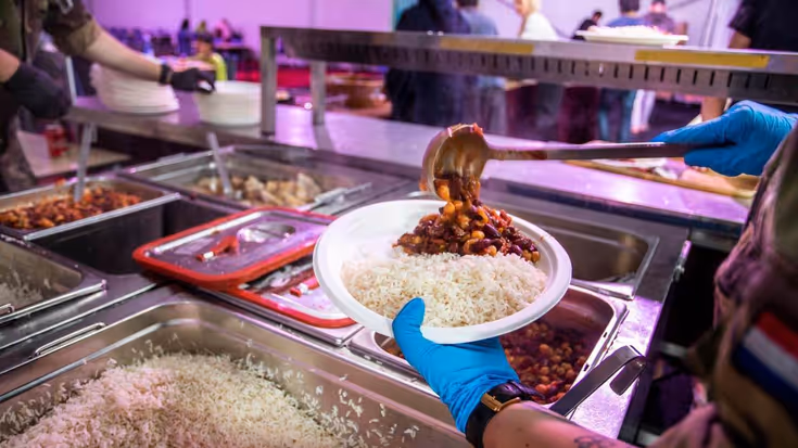 Militair schept bord rijst met chili op.