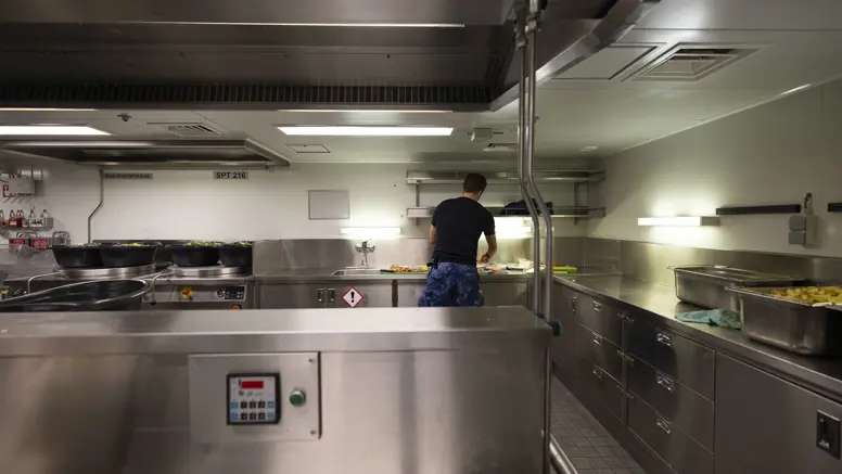 Een kok is aan het werk in een chromen keukenomgeving.