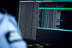 Een militair zit achter een beeldscherm waar gegevens op staan. 