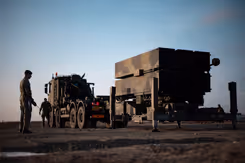 2 militairen staan bij een luchtafweersysteem. 