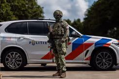 Militair poseert voor een politieauto.