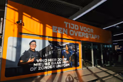 Grote oranje zuil en afbeelding van militairen. Tekst luidt: Tijd voor een overstap. Vind hier jouw baan met of zonder uniform.