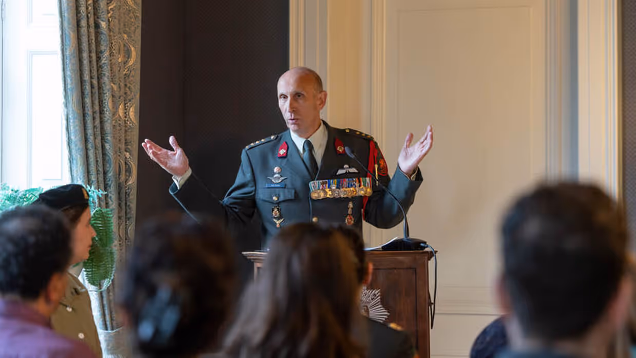 Militair spreekt zaal toe tijdens ceremonie.