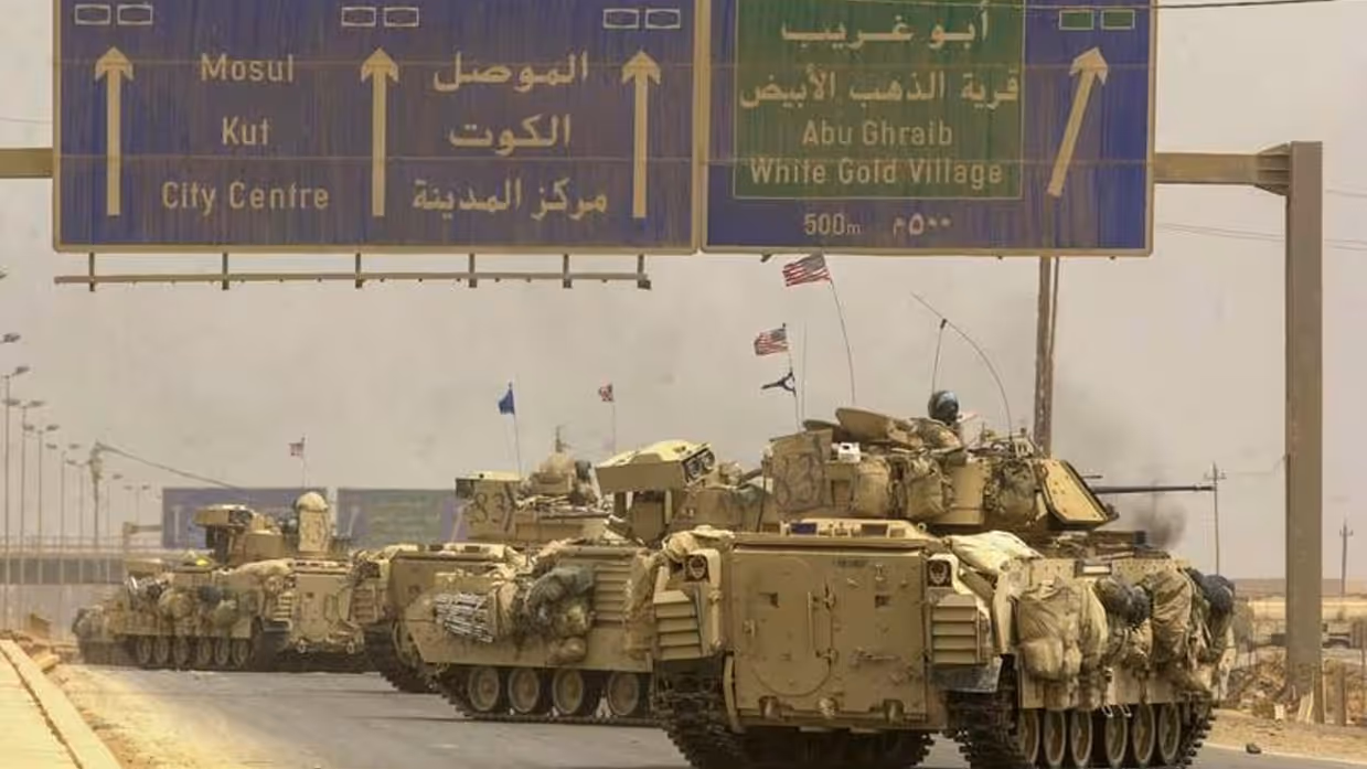 Links: Een rij militaire pantservoertuigen rijdt op weg naar Bagdad. Boven de weg staan verkeersborden met Mosul, Abu Ghraib en White Gold Village. Er zijn vlaggen te zien in een stoffig landschap. Rechts: Een pantserwagen staat op een stoffig, open veld. Op de achtergrond stijgt een dikke, zwarte rookkolom omhoog. Soldaten en uitrusting zijn zichtbaar rondom het voertuig.