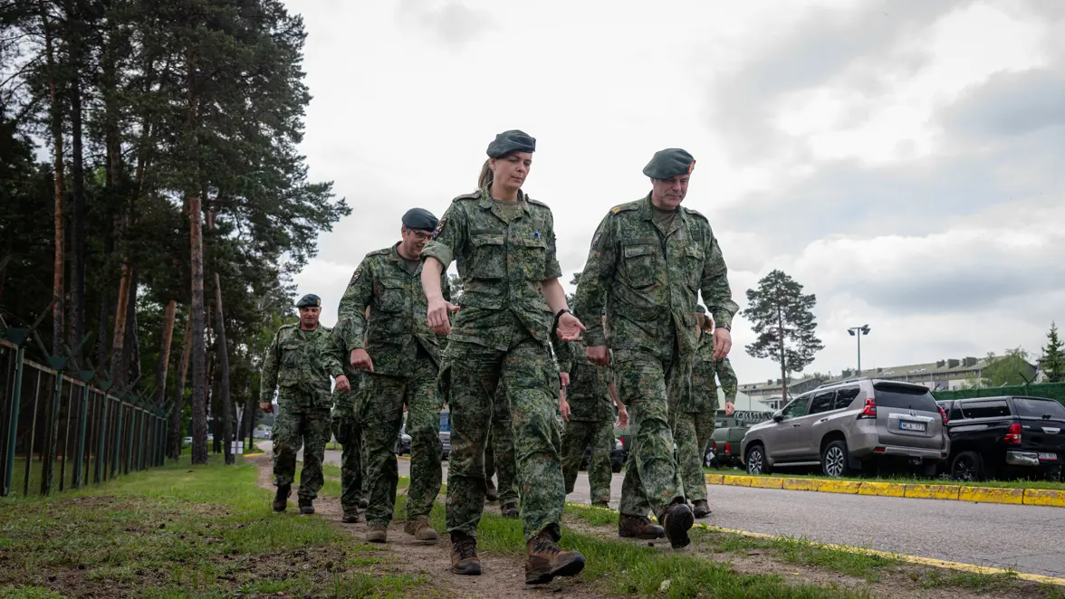 Militairen lopen door de berm van een weg. 