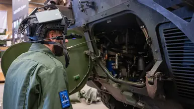Een monteur met een camera op zijn helm bij een voertuig. 