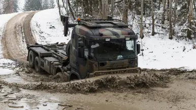 Een truck rijdt in de winter door sneeuw en modder.