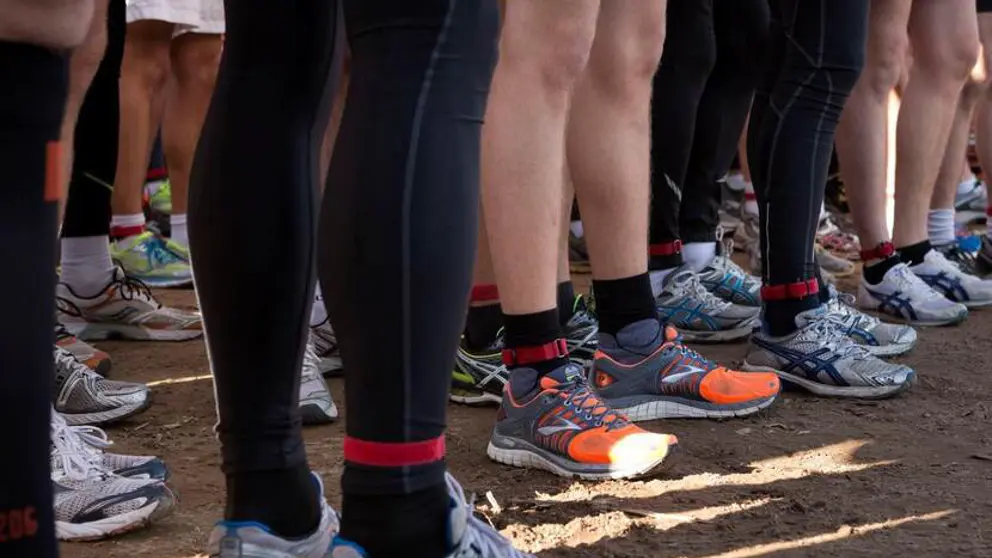 Benen van zo'n 10 sporters. Staan in groepje bij elkaar.