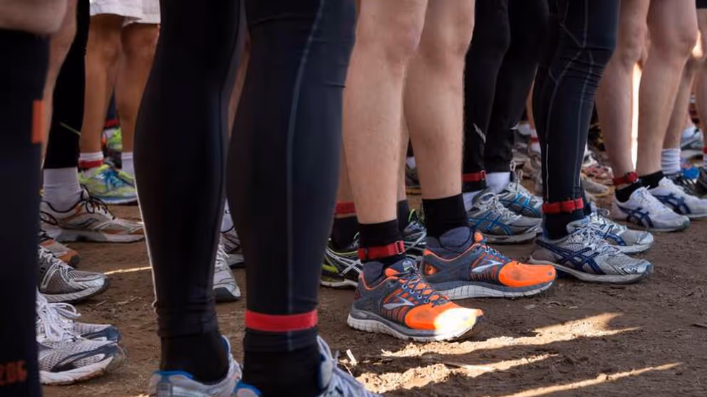Benen van zo'n 10 sporters. Staan in groepje bij elkaar.