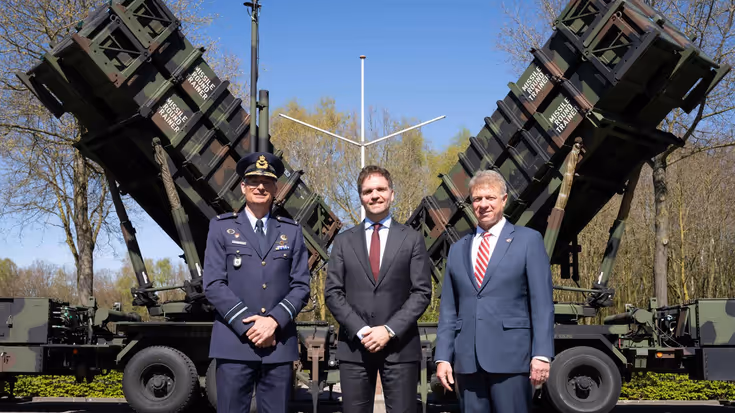De staatssecretaris en 2 anderen staan voor een Patriot. 