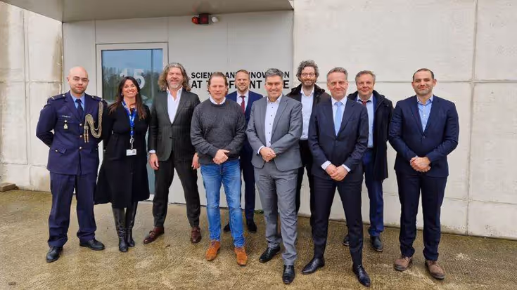 Mensen in pak poseren voor een groepsfoto.