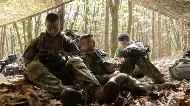 Militairen rusten en bereiden zich voor onder een gecamoufleerd schuilzeil.