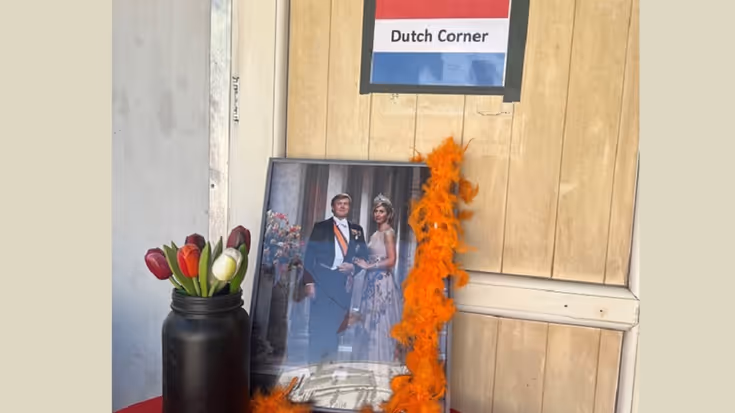 Foto van de koning en koningin met een vaas tulpen, met daarboven een bordje met: Dutch Corner, op een tafeltje in Irak. 
