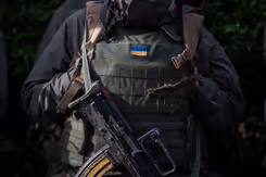 Militair met scherfvest, daarop een Oekraïens vlaggetje.