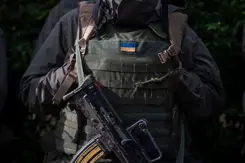 Militair met scherfvest, daarop een Oekraïens vlaggetje.