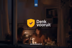 'Denk vooruit' staat op een foto genomen door een raam van 2 vrouwen en een kind die alleen kaarsjes aan hebben.